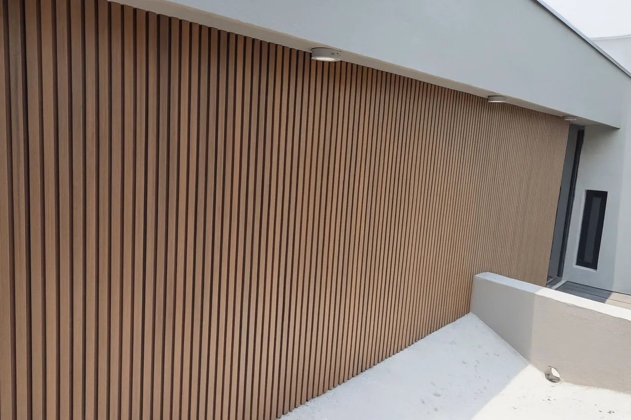 Muro de lambrín WPC vertical tono madera con una luz de techo